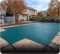 Pool safety cover securely installed over backyard swimming pool